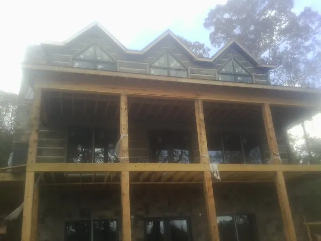 Dormers and porch framing on a large log home under construction — Roof Coating work by our crew in New Paris