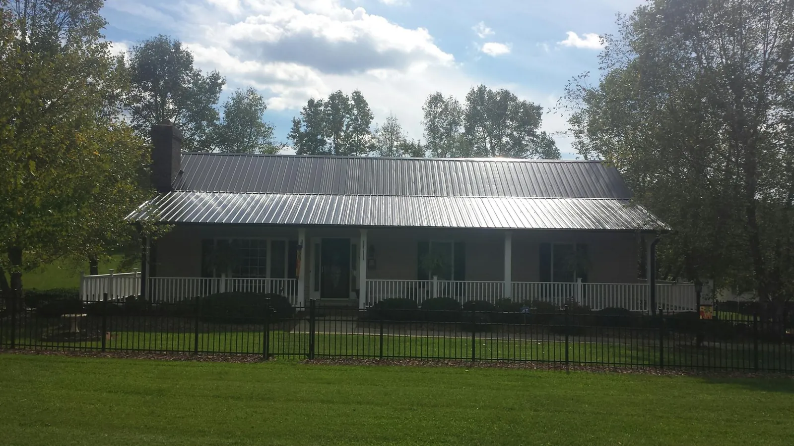 Gray metal roof on a brick ranch with a full width front porch — Gutter Guard Installation work by our crew in New Paris