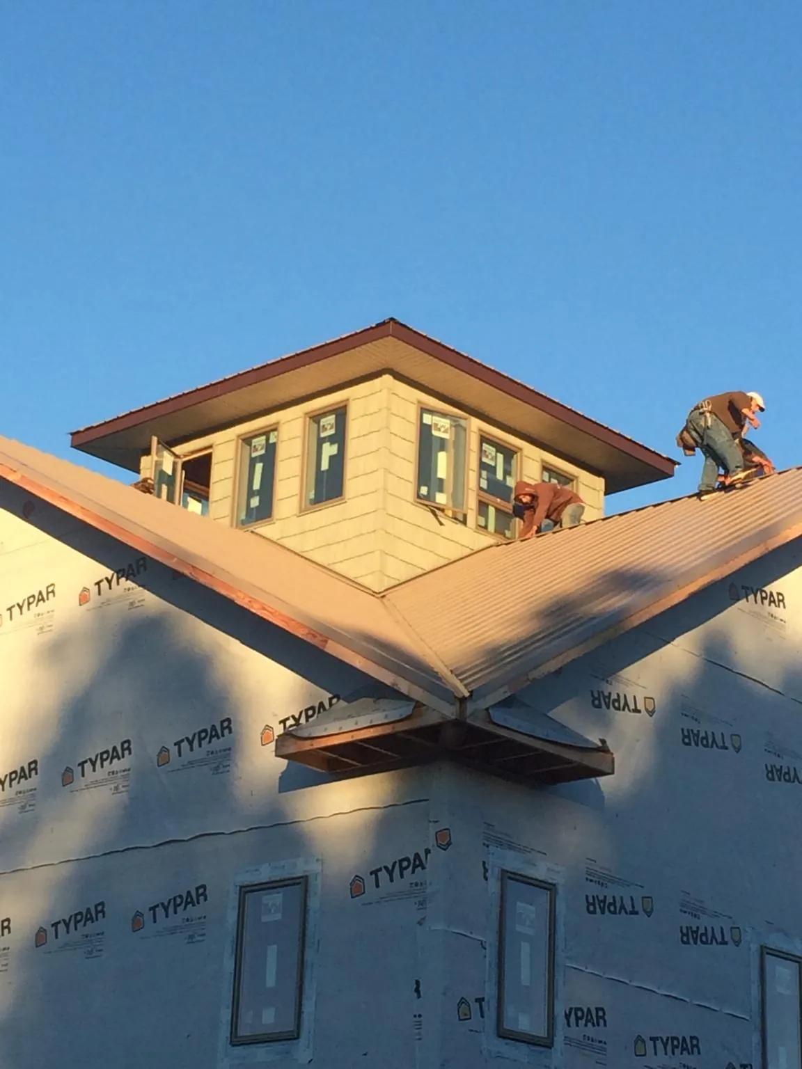 Roofers working around a rooftop cupola on a new metal roof at sunset — Roof Waterproofing in New Paris by Roofing Brothers